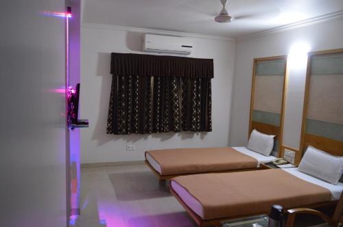a room with two beds and a window with purple lights at Hotel Easy Retreat in Vapi