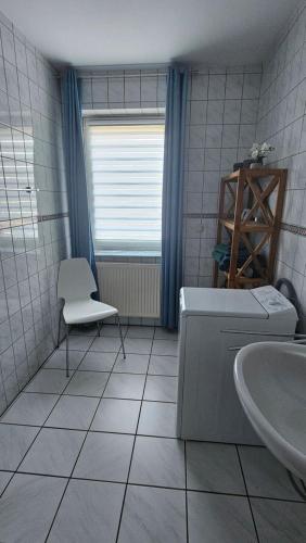 a bathroom with a tub and a sink and a chair at Ferienwohnung Werraglück in Eschwege