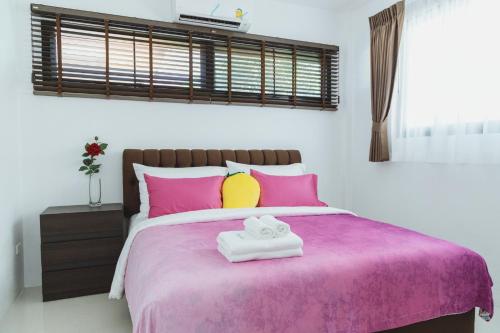 a bedroom with a bed with pink and yellow pillows at Baan Nern Khao Resort Pattaya in Ban Huai Yai