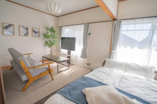 a bedroom with a bed and a chair and a tv at REKADO ROOM Kengun in Kumamoto