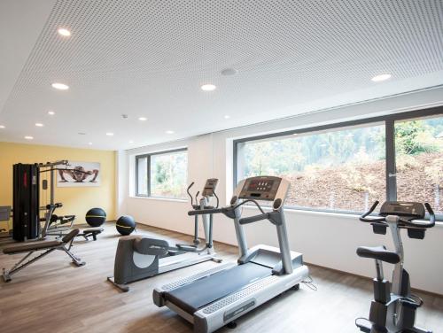 a gym with three tread machines and a window at Familienhotel Huber in Valles