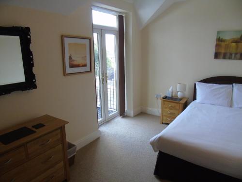 a bedroom with a bed and a dresser and a television at Jeffersons Abbey Road Serviced Apartments in Barrow in Furness