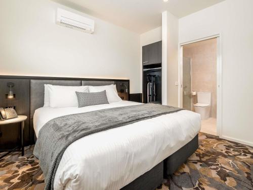 a bedroom with a large bed and a bathroom at Mantra Shepparton in Shepparton