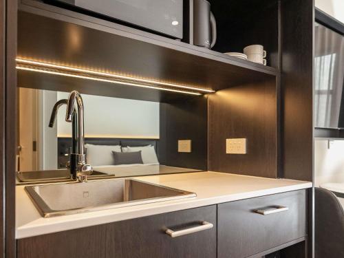 a kitchen with a sink and a mirror at Mantra Shepparton in Shepparton