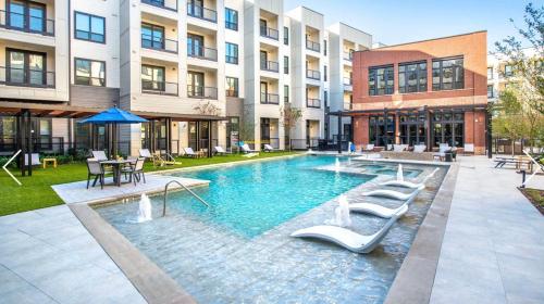 a swimming pool with lounge chairs in front of a building at 1200sf 2bed 2bath Apt near Medical City, Toyota Stadium and The Ford Center in Frisco