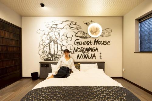 a man sitting on a bed in a bedroom at 旅宿信長と忍者---2階-忍者の間---NOBUNAGAtoNINJA in Omihachiman