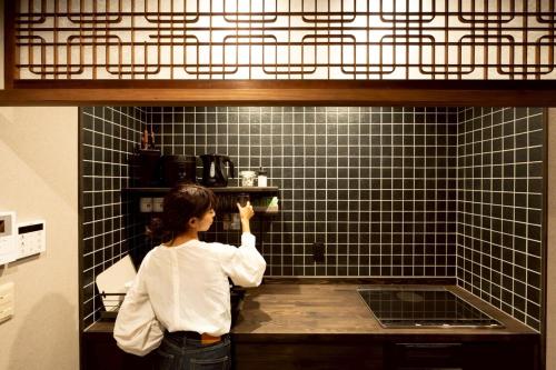 a woman standing in front of a counter in a kitchen at 旅宿信長と忍者---2階-忍者の間---NOBUNAGAtoNINJA in Omihachiman