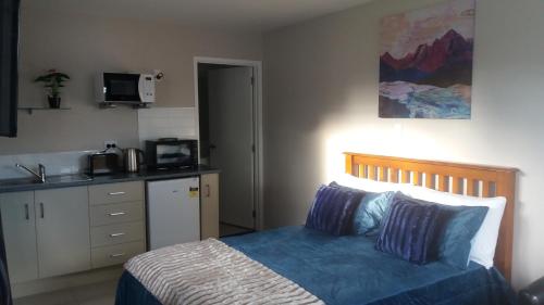 a small bedroom with a bed and a kitchen at Stream View in Christchurch