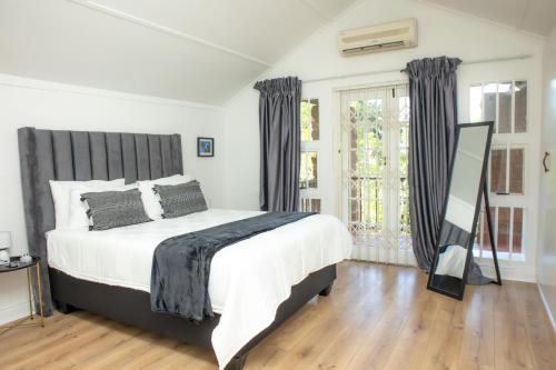 a bedroom with a bed and a large window at Black n Whyt Villa in Kloof