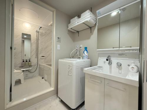 a white bathroom with a shower and a sink and a refrigerator at PRISM Inn Ikegami Kamata in Tokyo
