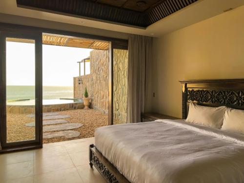 a bedroom with a bed and a view of the beach at Anket De' River Mui Ne resort in Mui Ne
