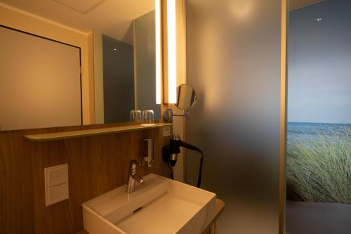 a bathroom with a sink and a mirror at DLRG Tagungszentrum Hotel Delphin in Bad Nenndorf
