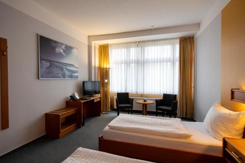 a hotel room with a bed and a desk and chairs at DLRG Tagungszentrum Hotel Delphin in Bad Nenndorf