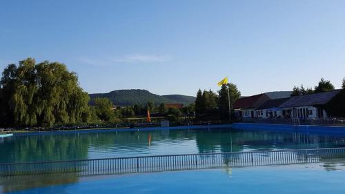 a large pool of water with a building and trees at Campingplatz am Hünstein in Nohra