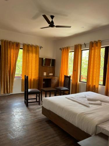 a bedroom with a bed and chairs and windows at The Walnut House in Pahalgām