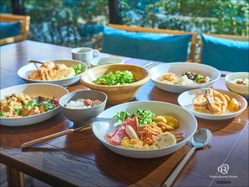 a wooden table topped with bowls of different foods at Daiwa Roynet Hotel Fukuyama Ekimae in Fukuyama