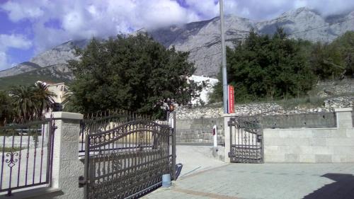 a gate in front of a house with mountains in the background at Apartments Malina in Tučepi