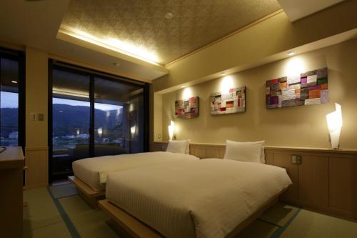 a bedroom with a large bed and a window at Fujikawaguchiko Onsen Konanso in Fujikawaguchiko