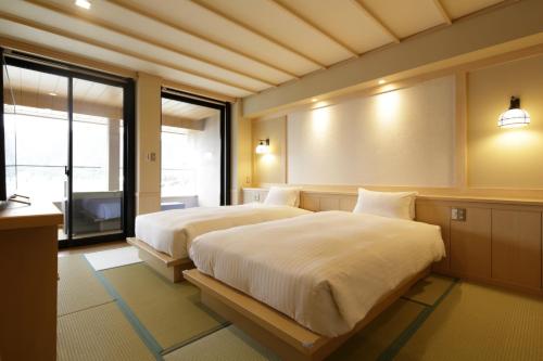 a bedroom with two beds and a large window at Fujikawaguchiko Onsen Konanso in Fujikawaguchiko