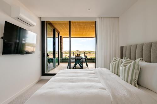 a bedroom with a bed and a balcony with a table at Winx Trackside Moonee Ponds in Moonee Ponds