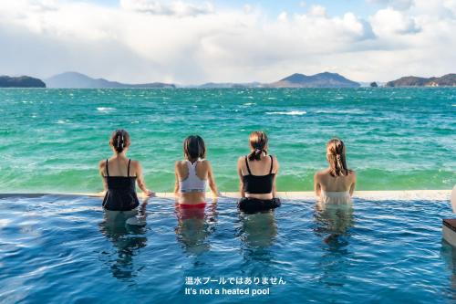three women sitting in the water in the ocean at Sunset SPA Resort AJI by SETO CLAS in Takamatsu