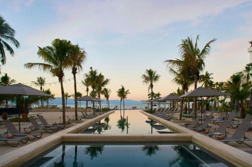 a resort pool with lounge chairs and palm trees at Marriott Puerto Vallarta Resort & Spa in Puerto Vallarta