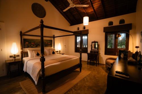 a bedroom with a canopy bed and a desk with a desk at Kirindi Paddy Isle - Boutique Villa in Negombo