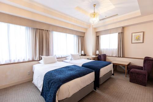 a hotel room with two beds and a chair at Hotel Rose Garden Shinjuku in Tokyo