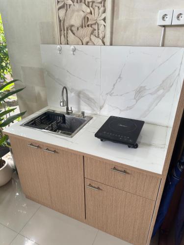 a kitchen counter with a sink and a laptop on it at Wisna House in Sanur