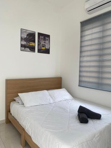 a bedroom with a bed with white sheets and a window at Izans Homestay Sendayan in Seremban