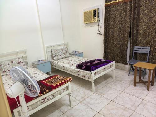 a room with two beds and a table and chairs at Catchy & Traveler-Friendly Room in Dibba