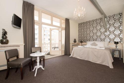 a bedroom with a bed and a table and a window at Hotel & Appartementen Bella Vista in Scheveningen