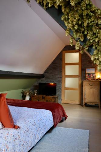 an attic bedroom with a bed and a television at Gîte & SPA du croquet in Blaringhem