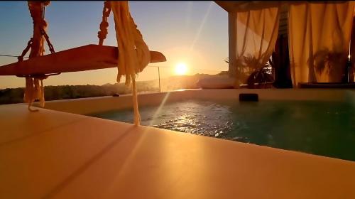 a bathtub with water pouring out of it with the sunset at One 360 Skyline Athens Penthouses in Athens