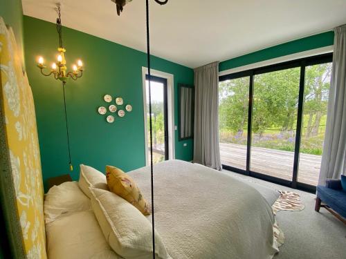 a bedroom with a large bed with a glass wall at Stablehouse Garden Shed in Masterton