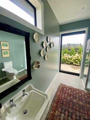 a bathroom with a sink and a mirror and a window at Stablehouse Garden Shed in Masterton