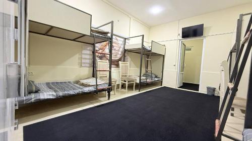 a room with three bunk beds and a carpet at Hostella in Salor Bekati