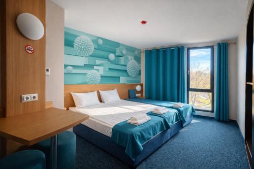 a bedroom with a bed and a desk and a window at WESTGATE Hotel - FREE PARKING in Veliko Tŭrnovo