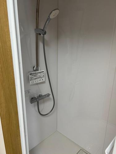 a shower with a shower head in a bathroom at Takamori Guest House in Takamori