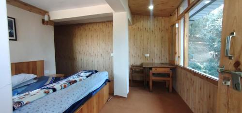 a bedroom with a bed and a desk and a window at Himalaya View in Rānīkhet
