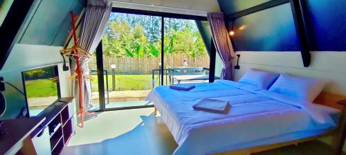 a bedroom with a bed and a large window at บ้านไม้หอมชาเล่ต์ in Suan Phung