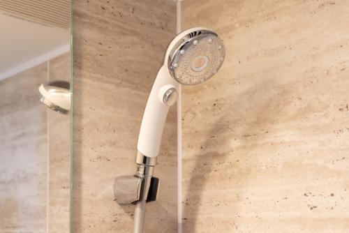 a shower head is attached to a glass door at LINKAGE STAY Chitose Funabashi in Tokyo