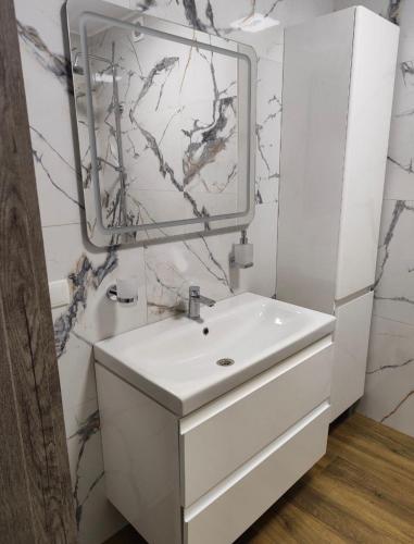 a white bathroom with a sink and a mirror at Дім весняний in Sheremetka