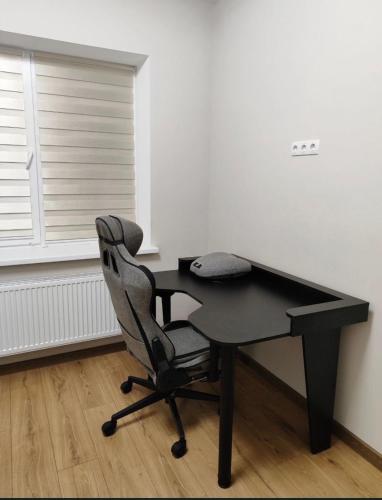 a black desk with a chair next to a window at Дім весняний in Sheremetka