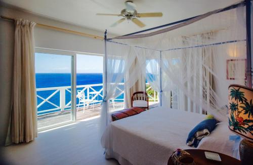 a bedroom with a bed and a view of the ocean at Dolcevita Cliff Private Resort by KlabHouse - Adults Only in English Harbour Town