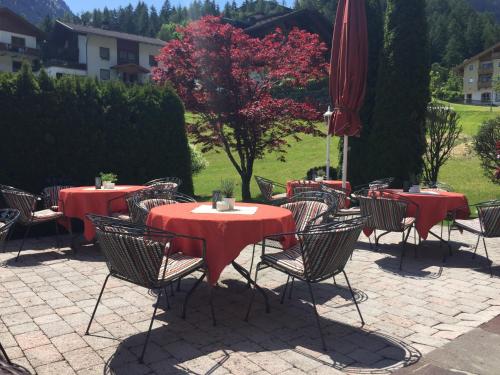 a group of tables and chairs with red tables and umbrellas at Olympia-Relax-Hotel Leonhard Stock in Finkenberg