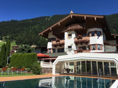 a large building with a swimming pool in front of it at Olympia-Relax-Hotel Leonhard Stock in Finkenberg