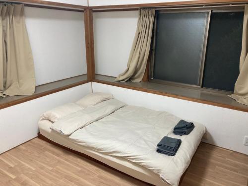 a small bed in a room with two windows at Vivi House in Kyoto