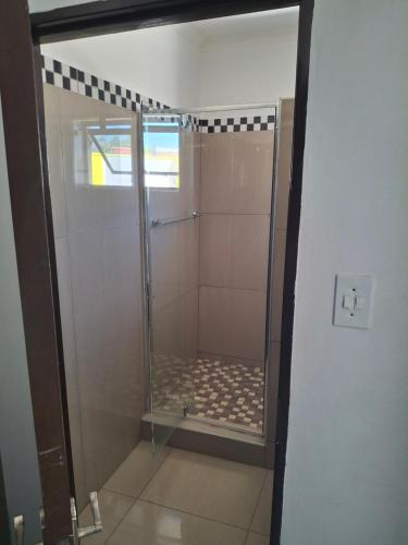 a shower with a glass door in a bathroom at Silk Mbare Guest House in Manzini