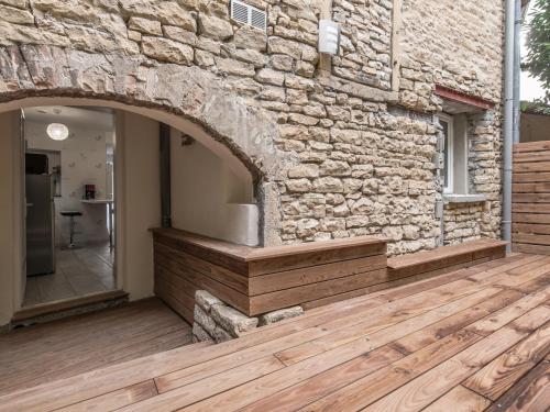 a stone wall with an archway on a wooden deck at Appart Hôtel Bourgoin in Bourgoin